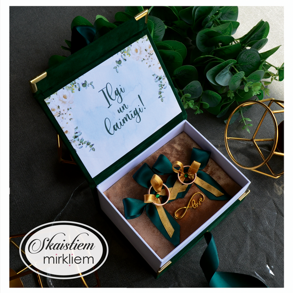 Tumši zaļa gredzenu kastīte ar personalizētu tekstu "Ilgi un laimīgi!" un zelta detaļām