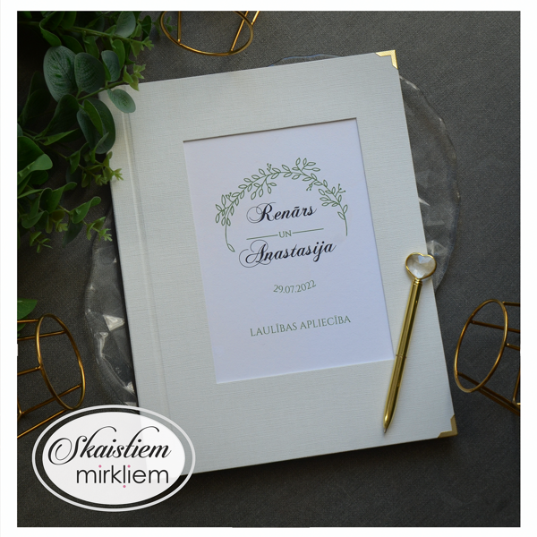 Gaiši laulības apliecības vāki ar zaļganu augu dizainu un vārdiem "Renārs un Annastasija"