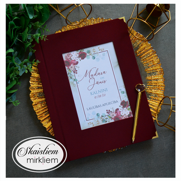 Sarkani laulības apliecības vāki ar ziedu vainagu un pāra vārdiem "Madara un Jānis"