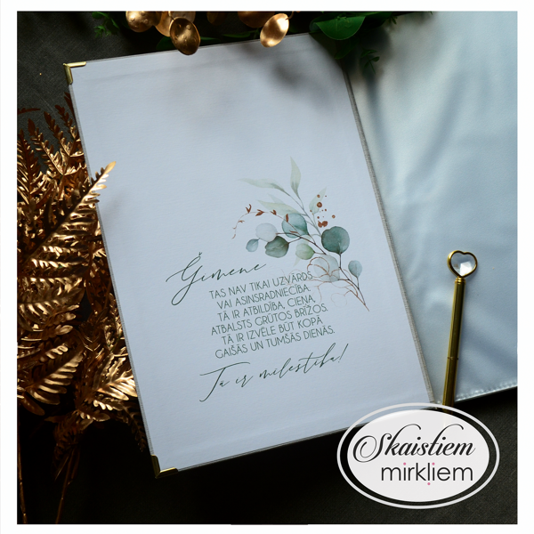 Atvērta pelēka laulības apliecības mape ar eikalipta lapu motīvu un emocionālu veltījumu