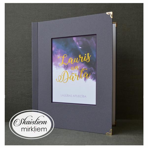Tumši pelēki laulības apliecības vāki ar košu zelta apdruku "Lauris un Dārta"