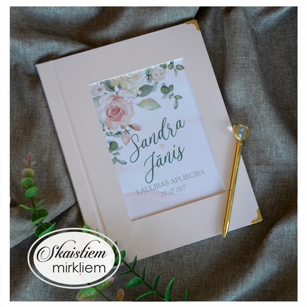 Rozā laulības apliecības mape ar zaļganu ziedu motīvu un pāra vārdiem "Sandra un Jānis"