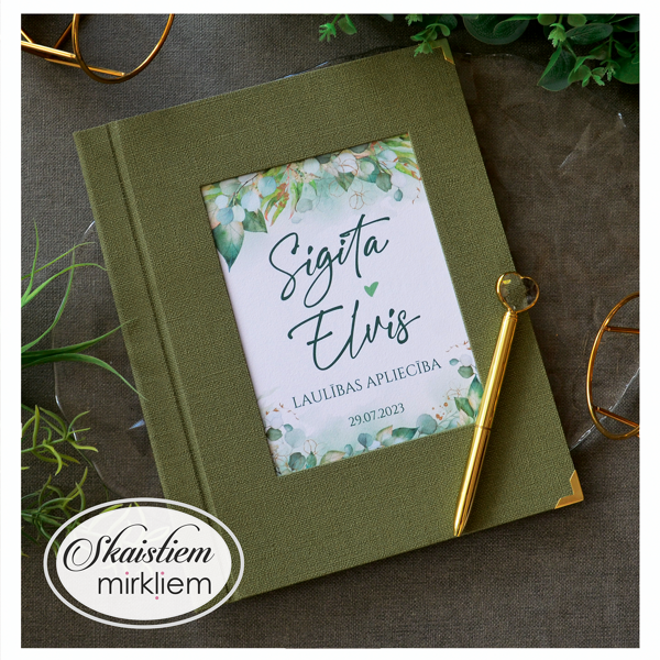 Sūnzaļas krāsas laulības apliecības vāki ar lapiņam un vārdiem "Sigita un Elvis"