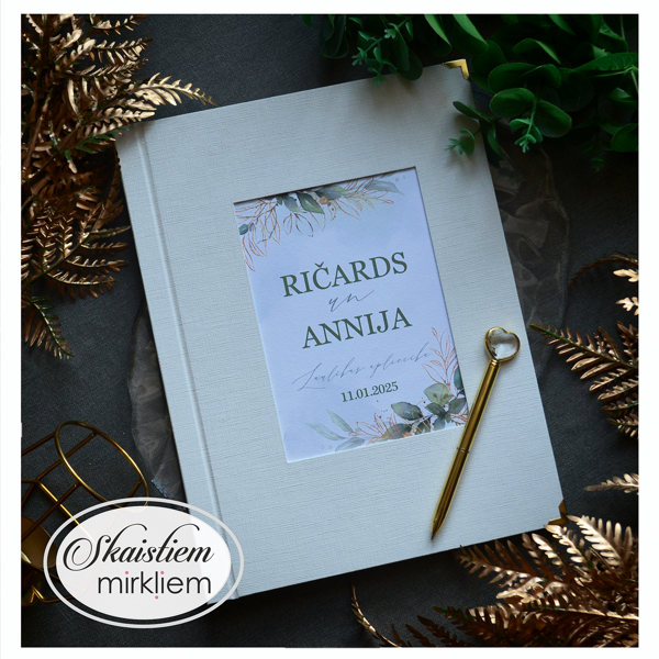 Pienbalti laulības apliecības vāki ar lapu motīvu un vārdiem "Ričards un Annija"