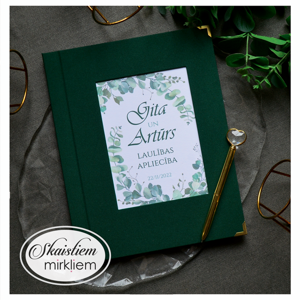 Tumši zaļas krāsas laulības apliecības mape ar eikalipta lapu motīvu un vārdiem "Gita un A