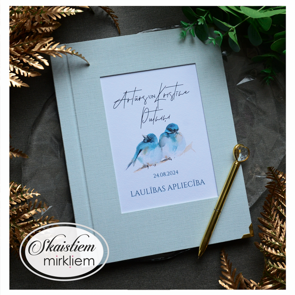 Maigi zili laulības apliecības vāki ar divu putnu ilustrāciju un vārdiem