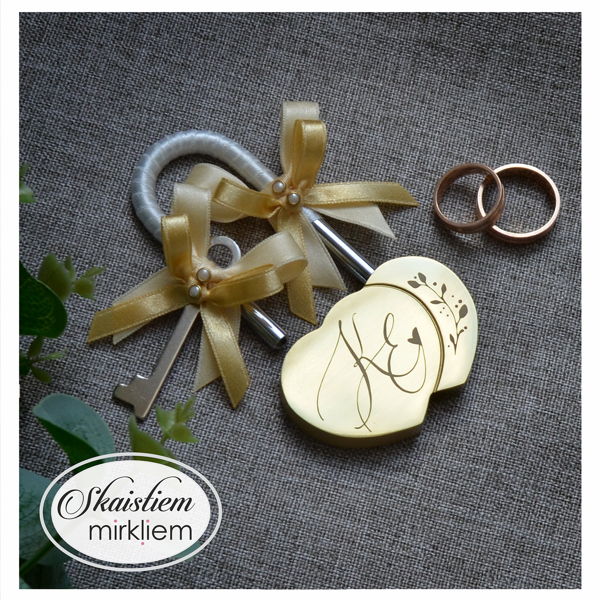 Personalizēta slēdzene ar iniciāļiem K un J, lapiņu motīvu un zeltainu dekoratīvo lentīti