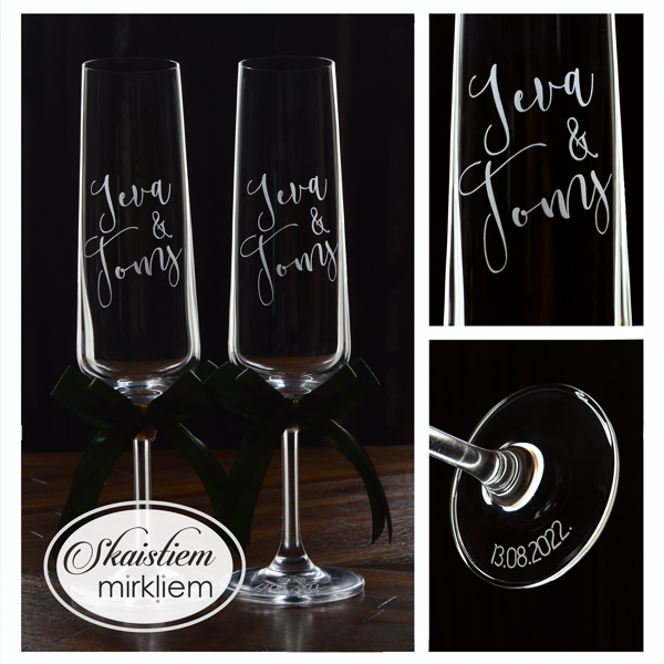 Klasiskas kāzu glāzes ar vārdu gravējumu un tumši zaļām dekoratīvajām lentēm