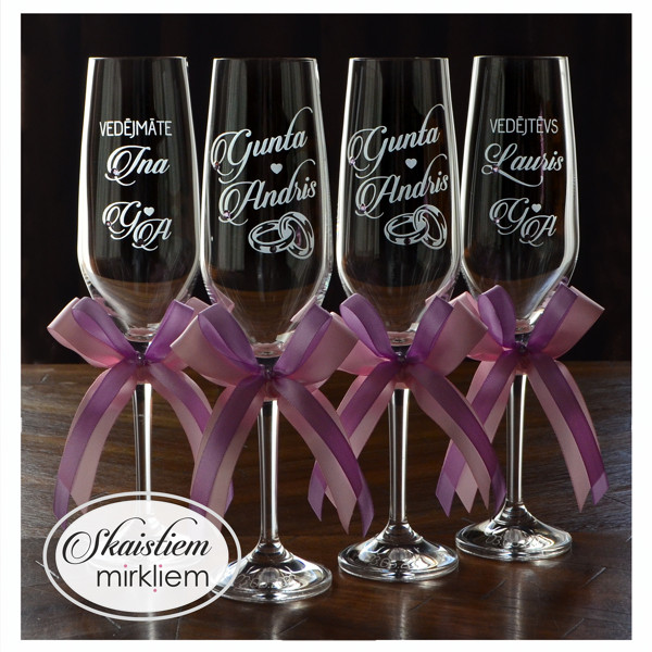 Kāzu glāzes ar gredzenu motīva gravējumu un gaiši violetām un rozā lentēm