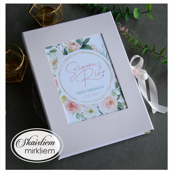 Maigi rozā viesu grāmata ar apaļu ziedu vainaga printu vāka centrā un pūderkrāsas lenti