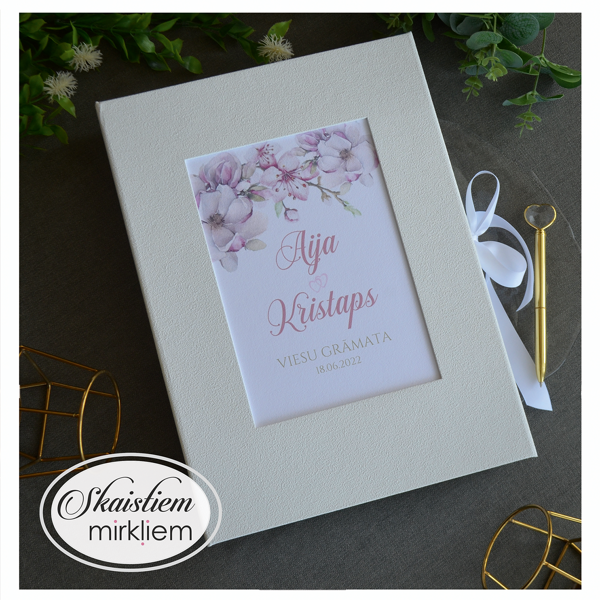 Viesu grāmata ar ābeļziedu printu vāka kreisajā pusē un vietu viesu anketām