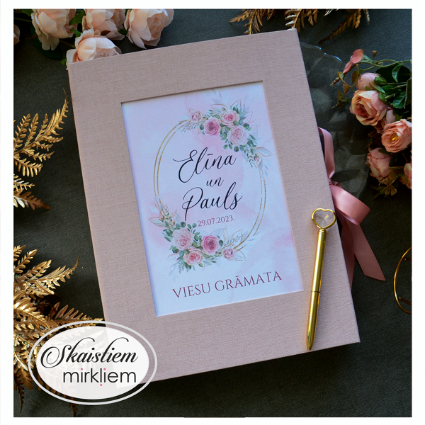 Rozā viesu grāmata ar ziedu motīvu centrā un viesu anketas lapām