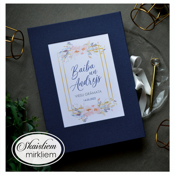 Tumši zila viesu grāmata ar zelta sešstūra rāmja printu un maigu ziedu kompozīciju centrā