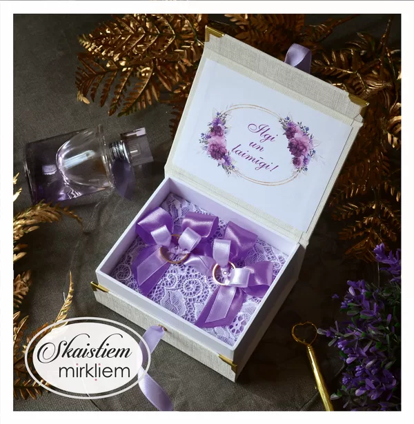 Eleganta balta kastīte gredzeniem ar violetu ziedu dekoru un gaiši violetu lenti