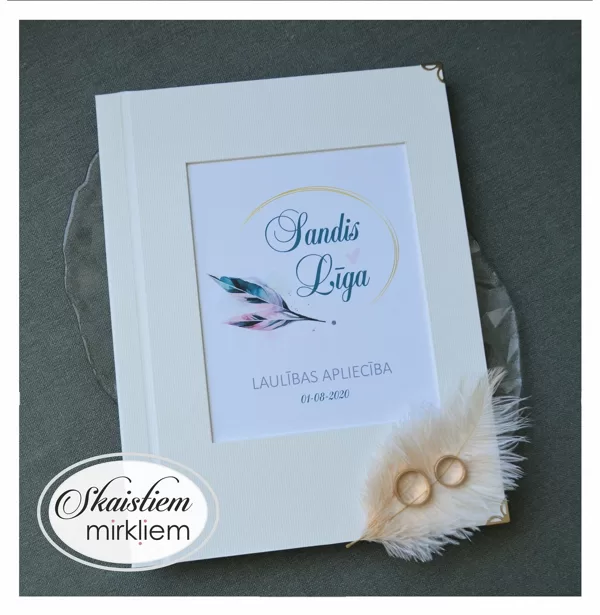 Gaiši laulības apliecības vāki ar spalvas motīvu un vārdiem "Sandis un Līga"