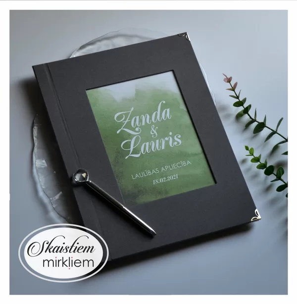 Tumši pelēki laulības apliecības vāki ar zaļu akvareli un vārdiem "Zanda un Lauris"