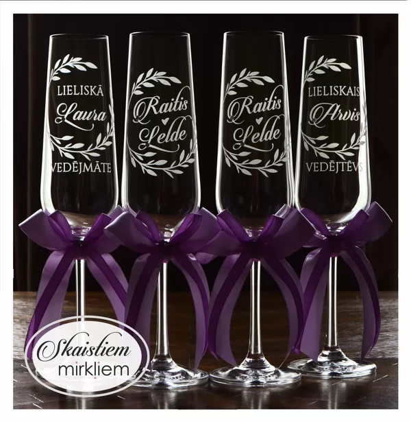 Elegantas kāzu glāzes ar lapu vainaga gravējumu un violetām lentēm